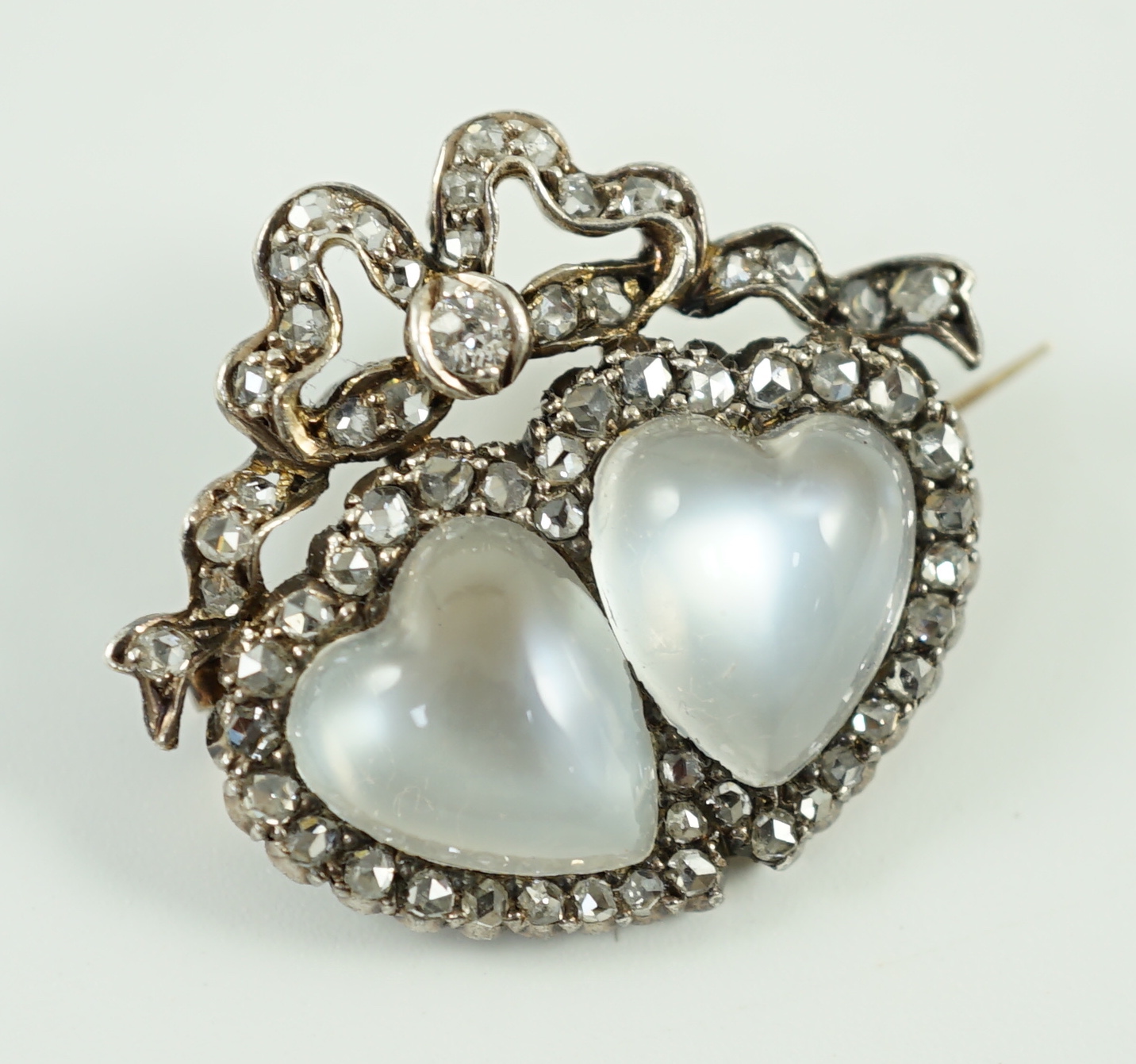 An Edwardian gold and silver, moonstone and diamond cluster set twin hearts brooch